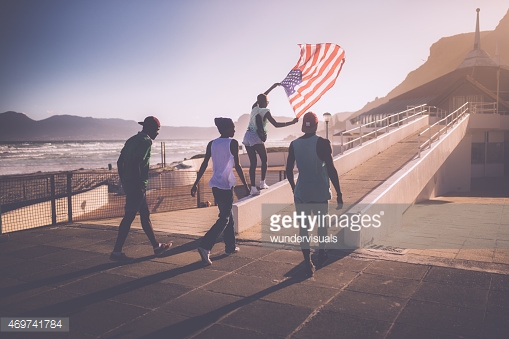 Teenage African American teenager flying an American flag at beach